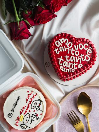 Mãos segurando bentô cake de coração vermelho com a frase 'amo você tanto tanto' – Auris Doceria