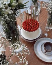 Bolo branco coberto de morangos frescos em mesa de festa